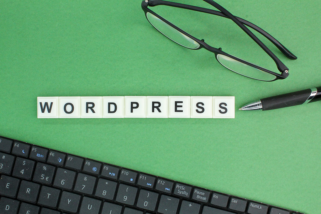 Le mot WordPress épelé sur fond vert avec des lunettes et un clavier, illustrant la migration de Joomla vers WordPress